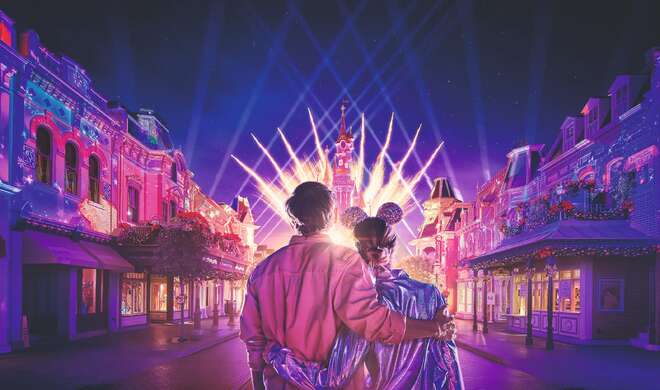 Una giovane coppia, vista di spalle, osserva lo spettacolo di luci serale, di fronte al castello Disneyland